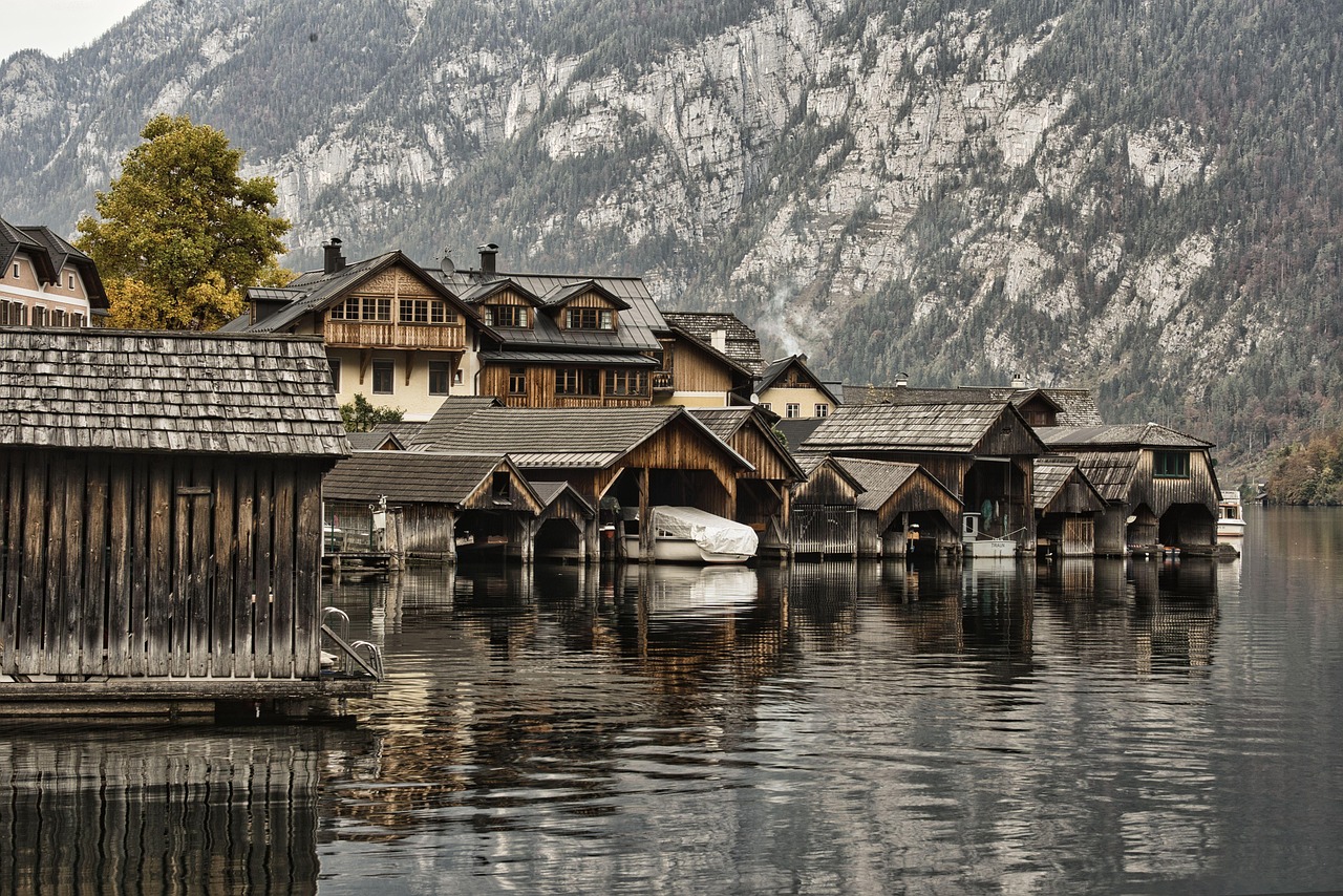 Wooden boathouses standing in the shallows of the Hallstattersee below timber-fronted village buildings