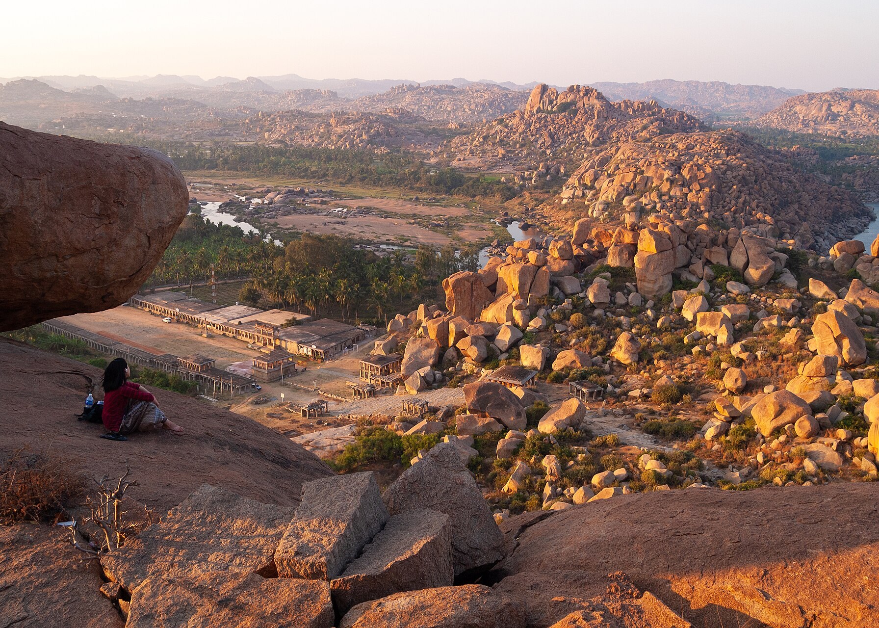 A traveller dwarfed among the giant balanced granite boulders of Hampi at golden hour