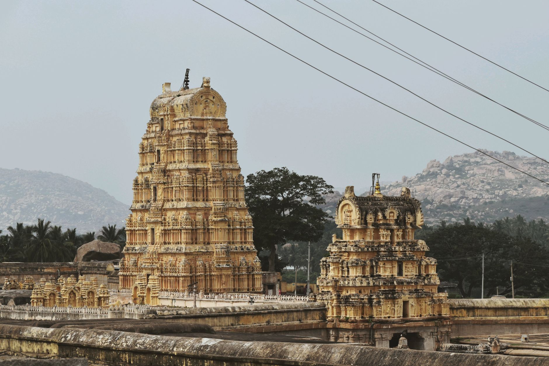 The nine-tiered gopuram tower of the Virupaksha temple rising over the ruins of Hampi in golden light