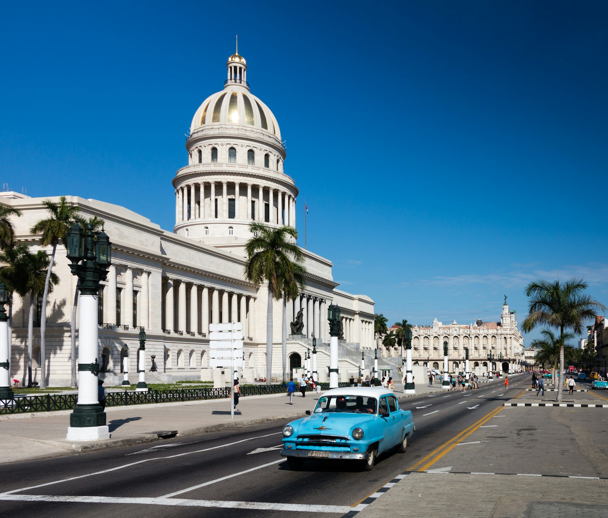 The domed neoclassical El Capitolio in Havana with a turquoise 1950s car passing in front