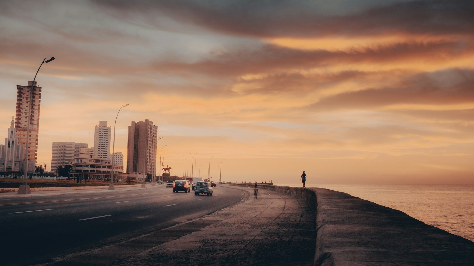 The Malecon seawall road curving along the Havana waterfront at sunset with apartment towers behind