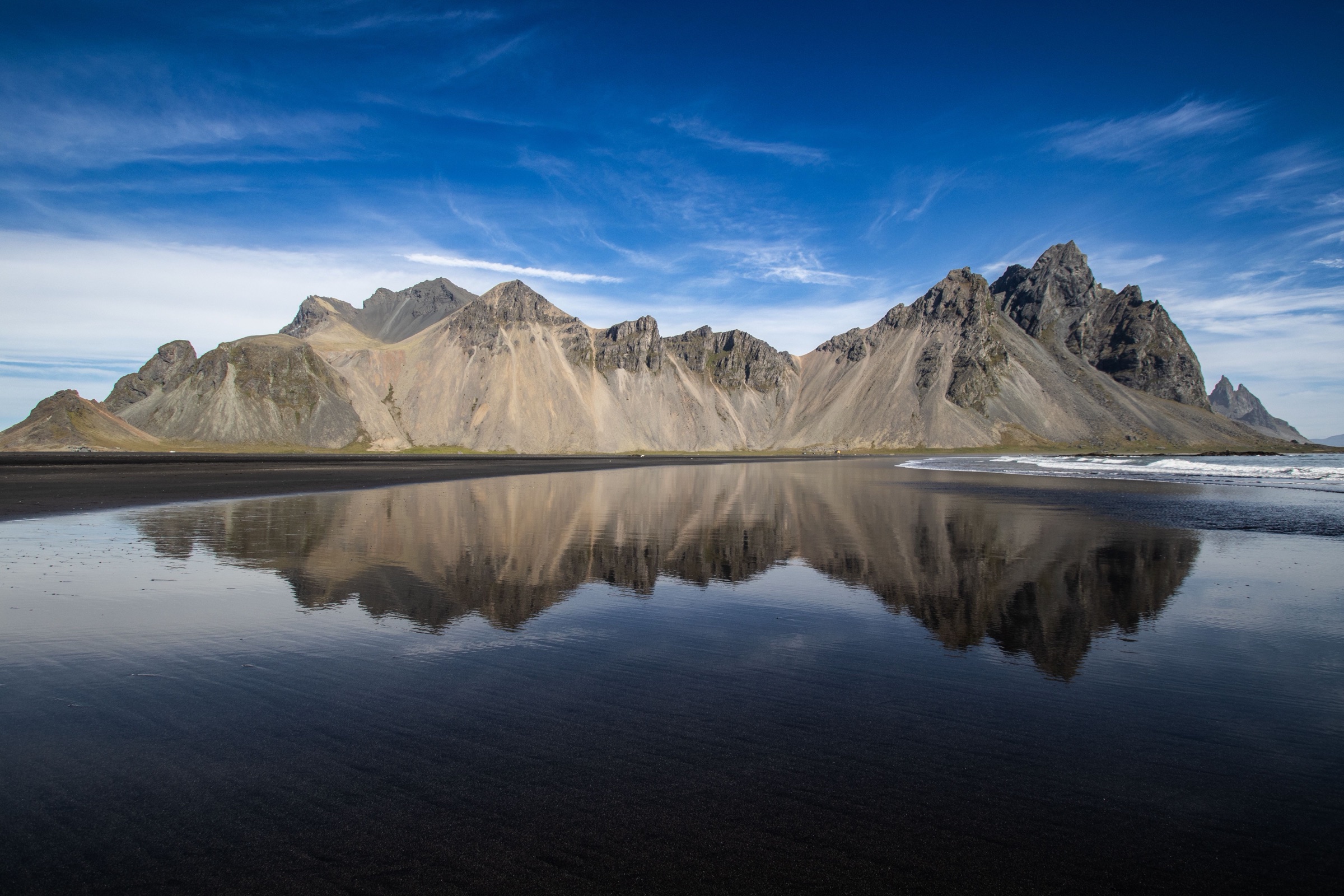 Vestrahorn's jagged ridge mirrored in wet black sand at Stokksnes