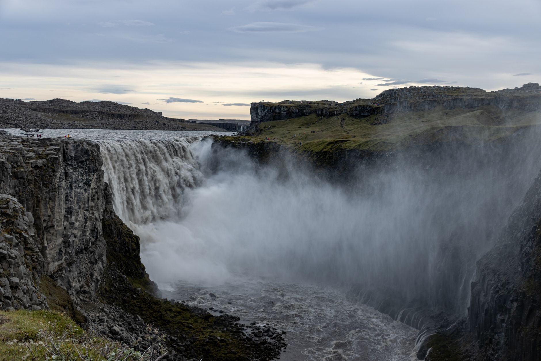 Dettifoss pouring grey glacial water into a deep basalt canyon, spray filling the gorge