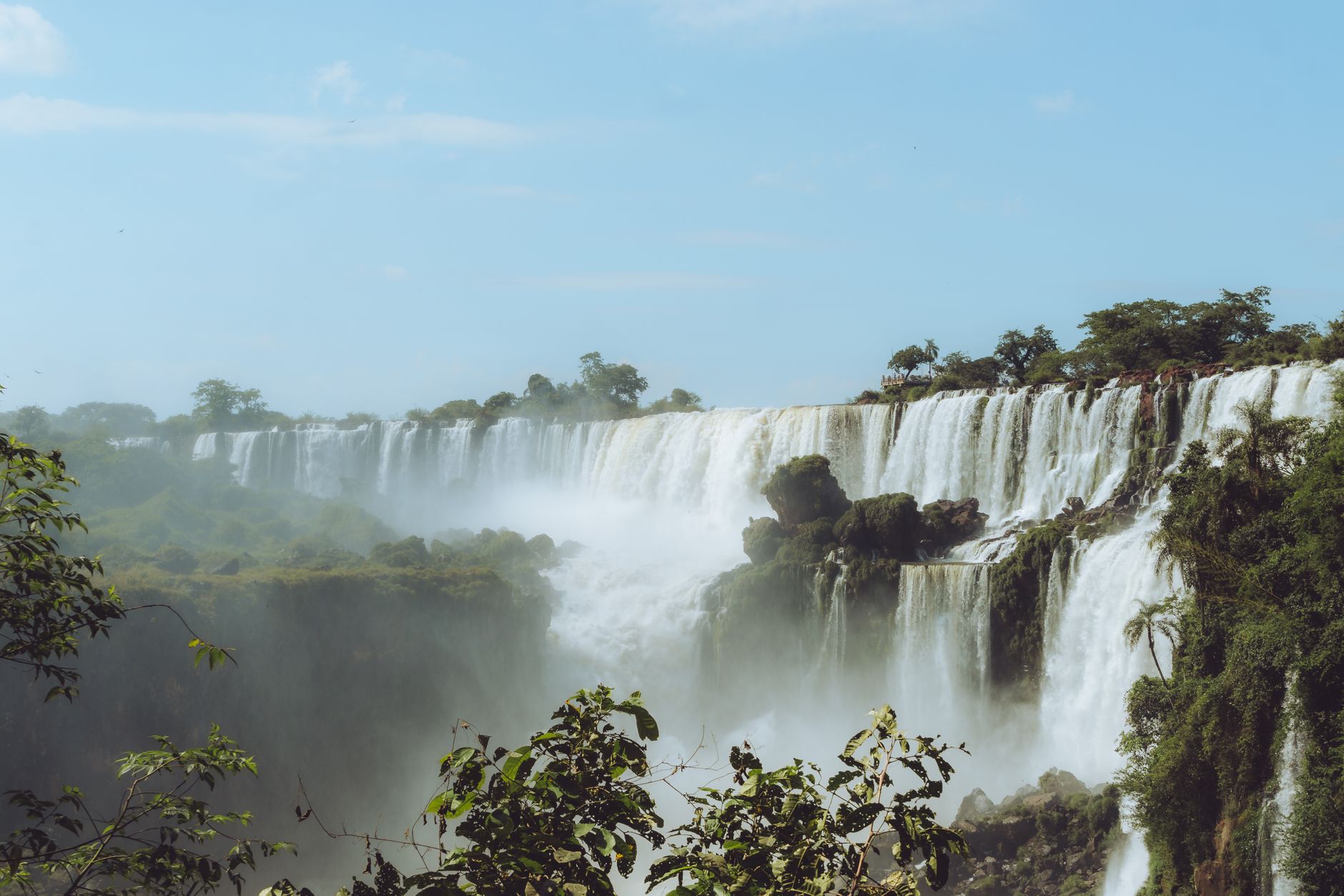 Curtains of white water pouring into a misty horseshoe framed by green forest, the Devil's Throat at Iguacu