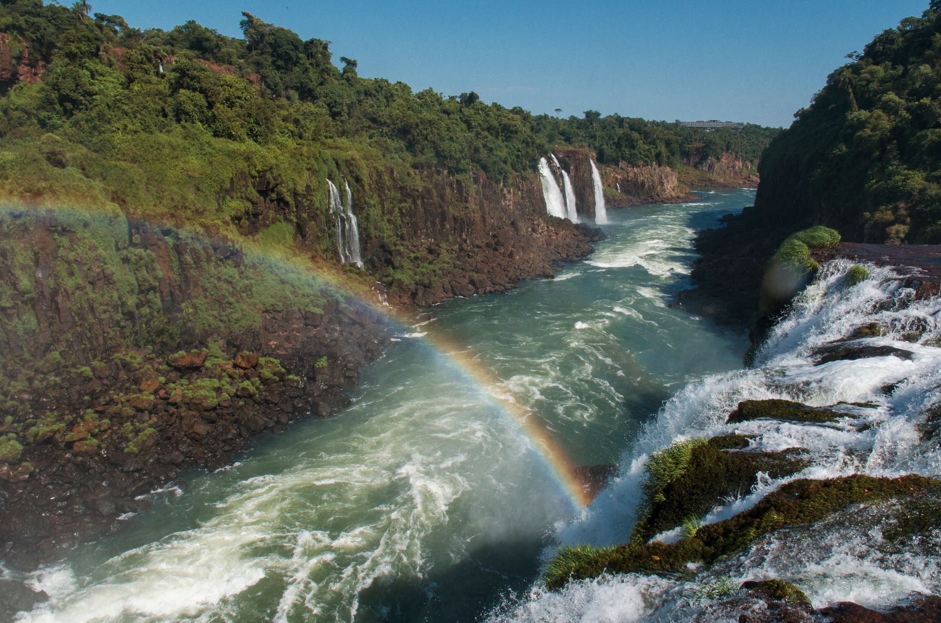 A rainbow arcing across the Iguacu gorge, white cataracts falling into the river between walls of green forest