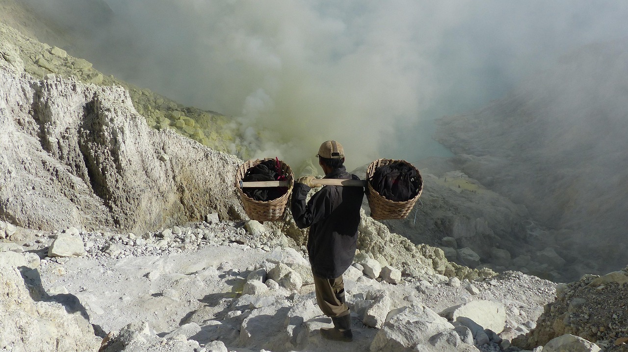 Figures in gas masks moving through sulphur smoke on the crater floor of Kawah Ijen