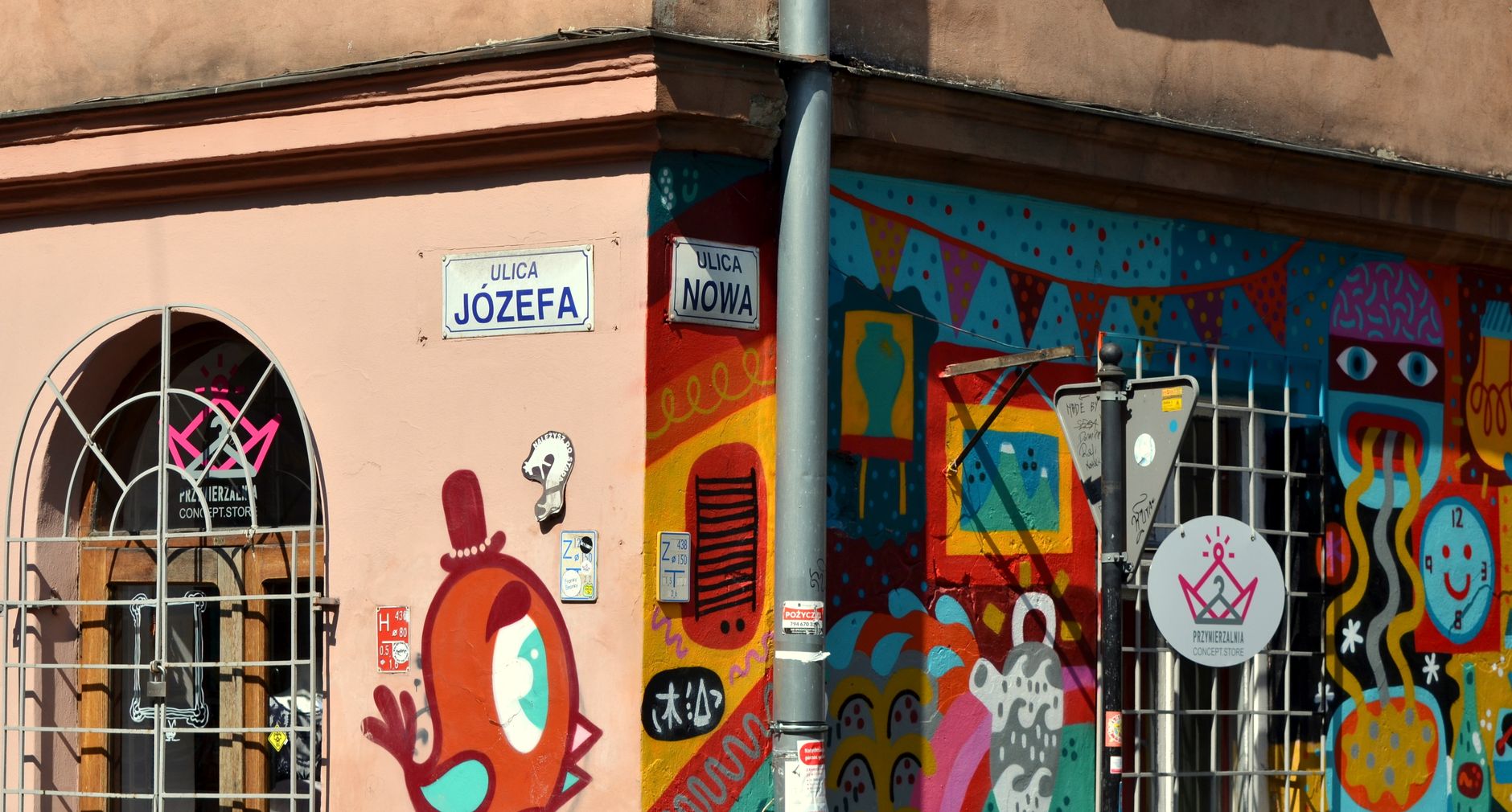 A corner building on Jozefa street in Kazimierz covered in bright street art, with the street sign visible