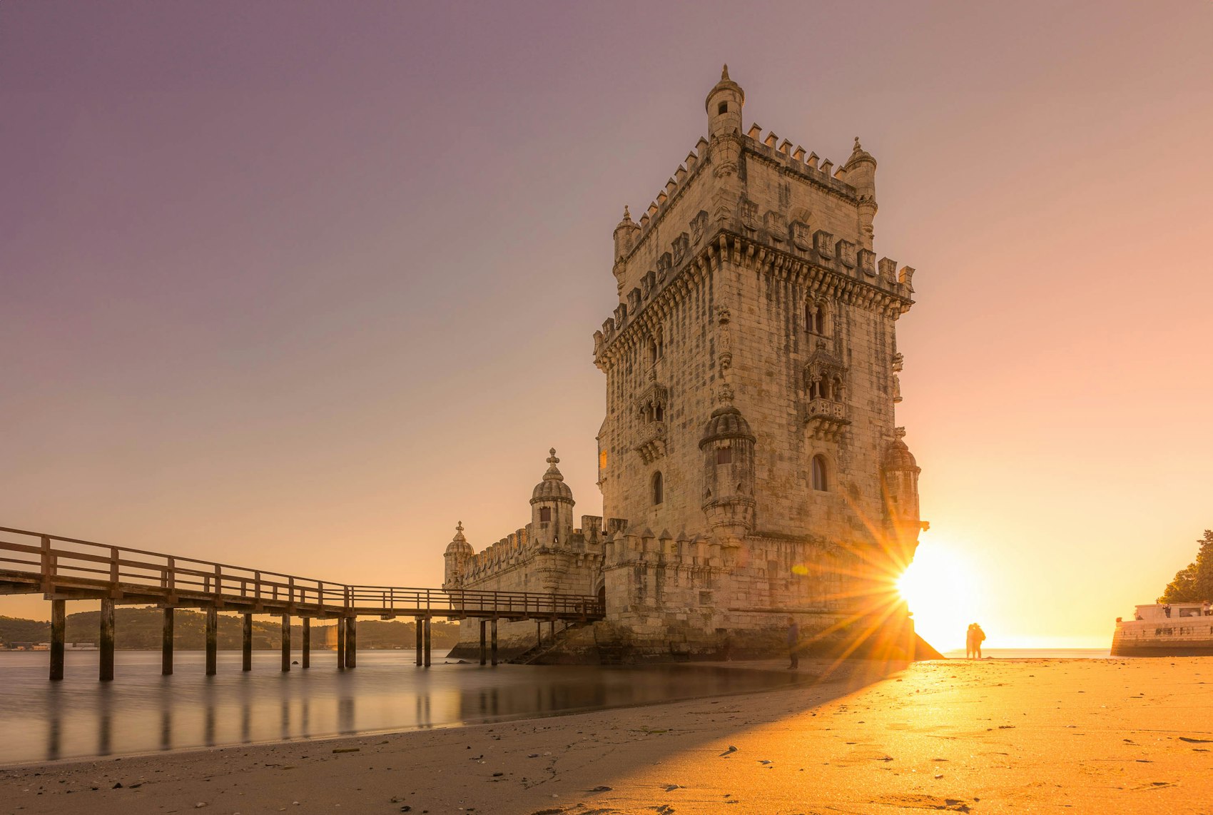 The Belém Tower standing in the water at sunset in Lisbon