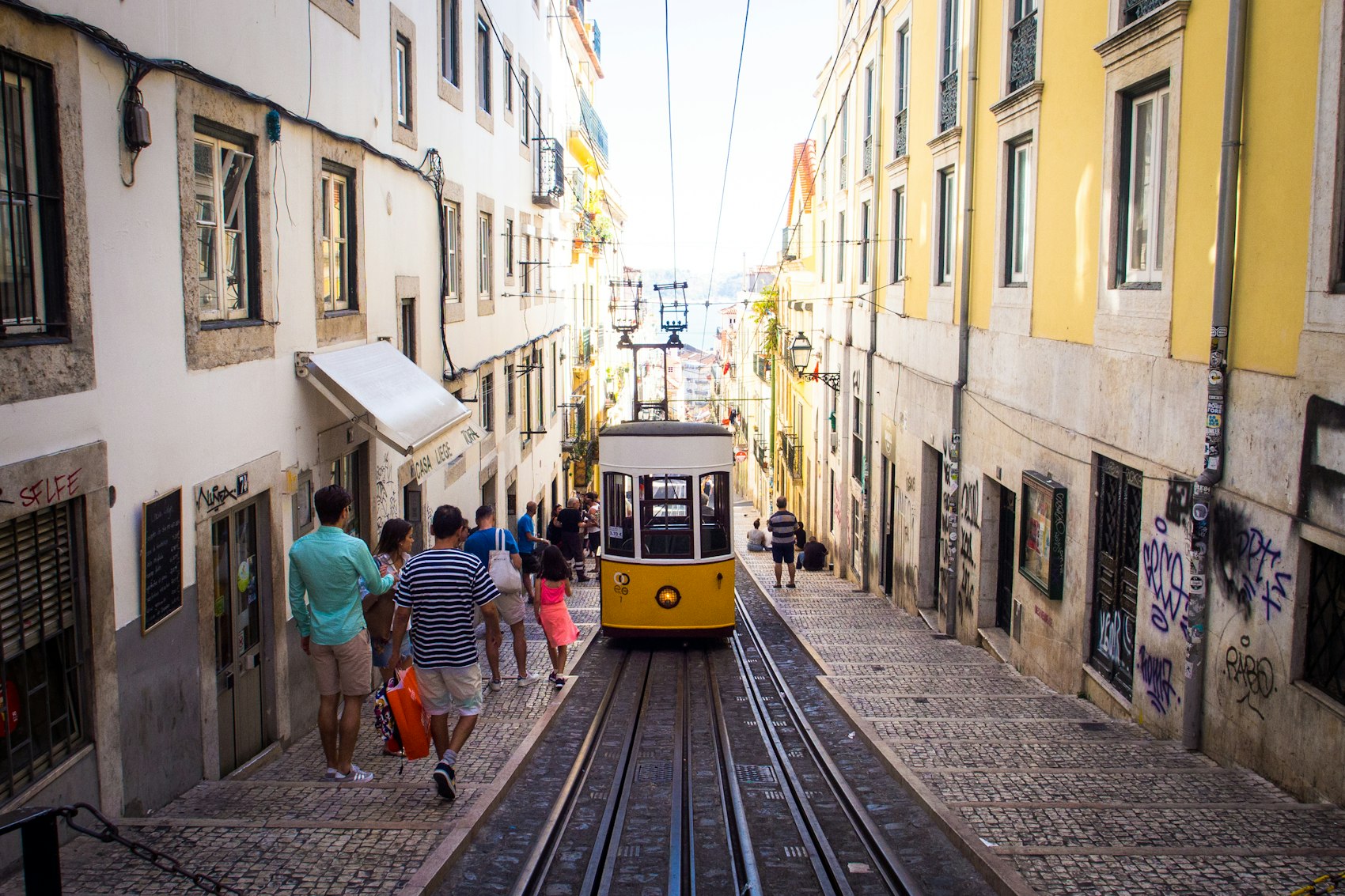 The yellow Bica funicular climbing a steep narrow street in Lisbon