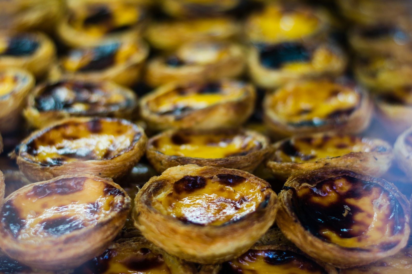 A tray of pastéis de nata with scorched tops, fresh from the oven