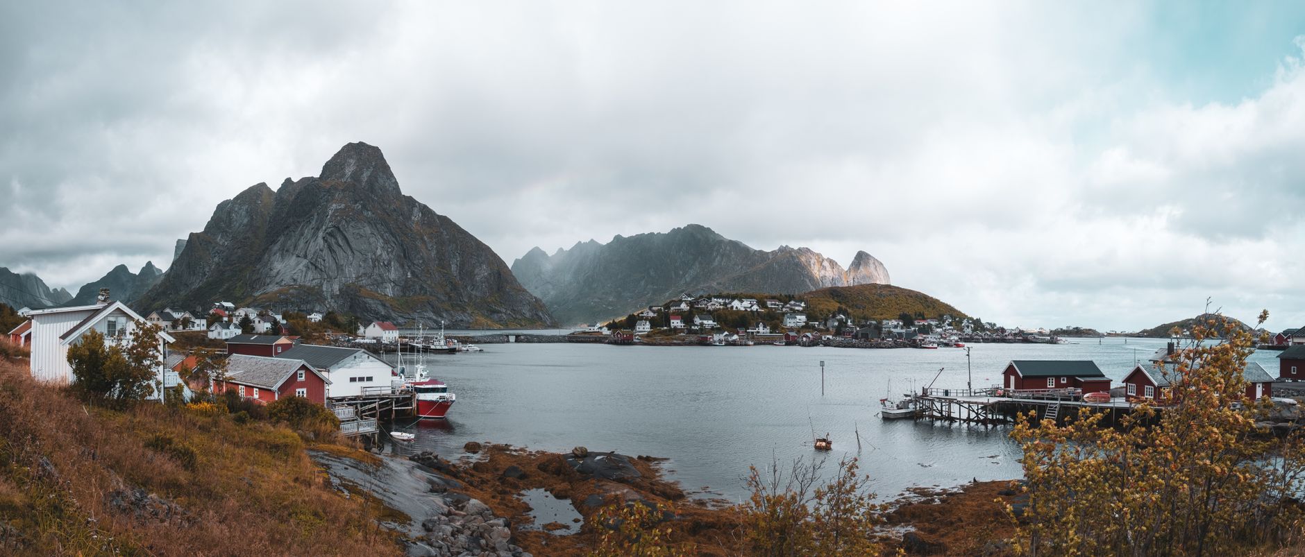 The village of Reine under mist-covered peaks, red and white houses along a grey inlet