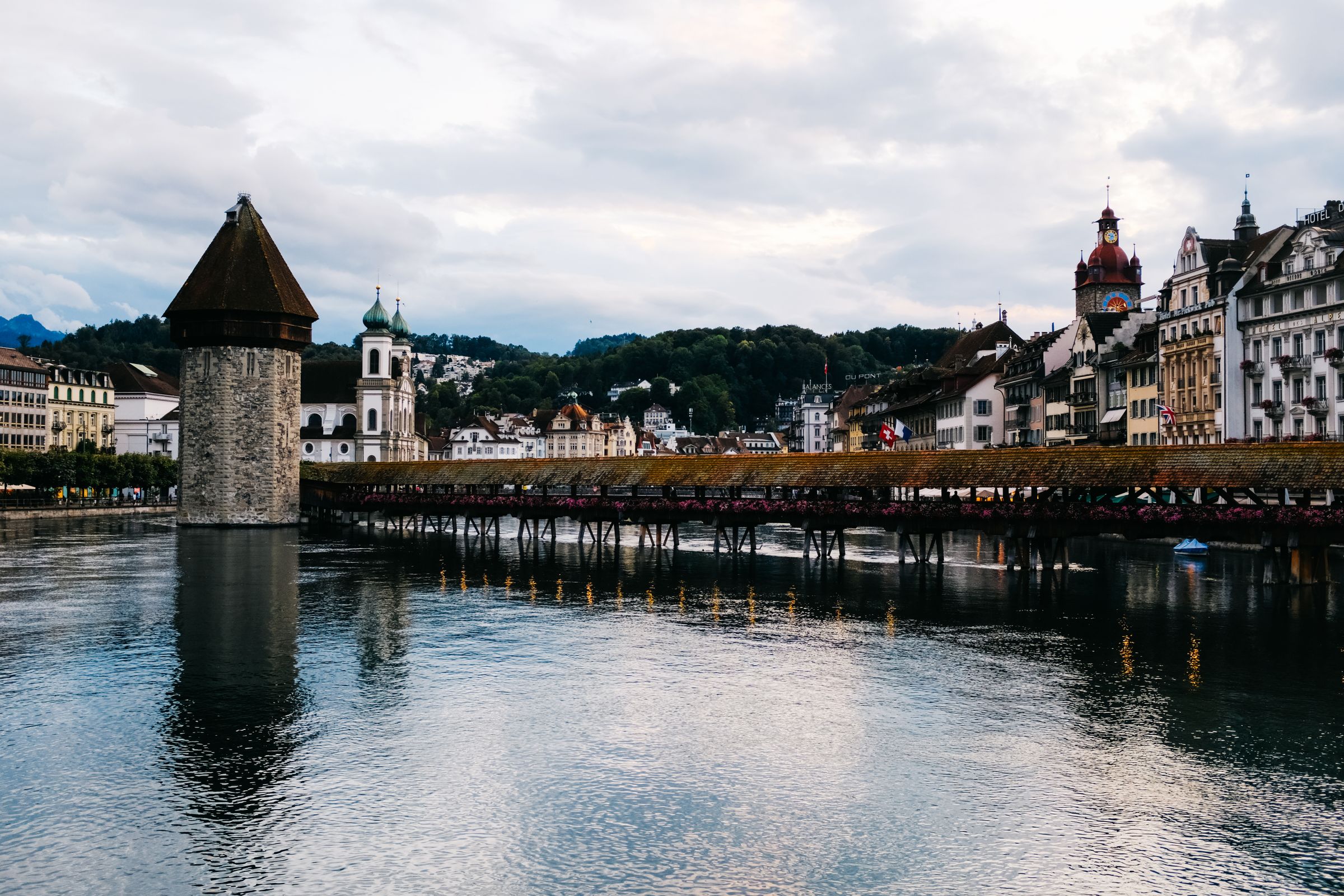 The Chapel Bridge and the stone Water Tower across the Reuss in Lucerne, with the Jesuit Church's domes and the town hall clock tower behind