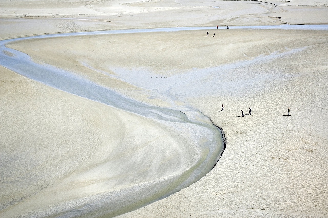 Walkers crossing the vast sand flats of the bay of Mont-Saint-Michel at low tide