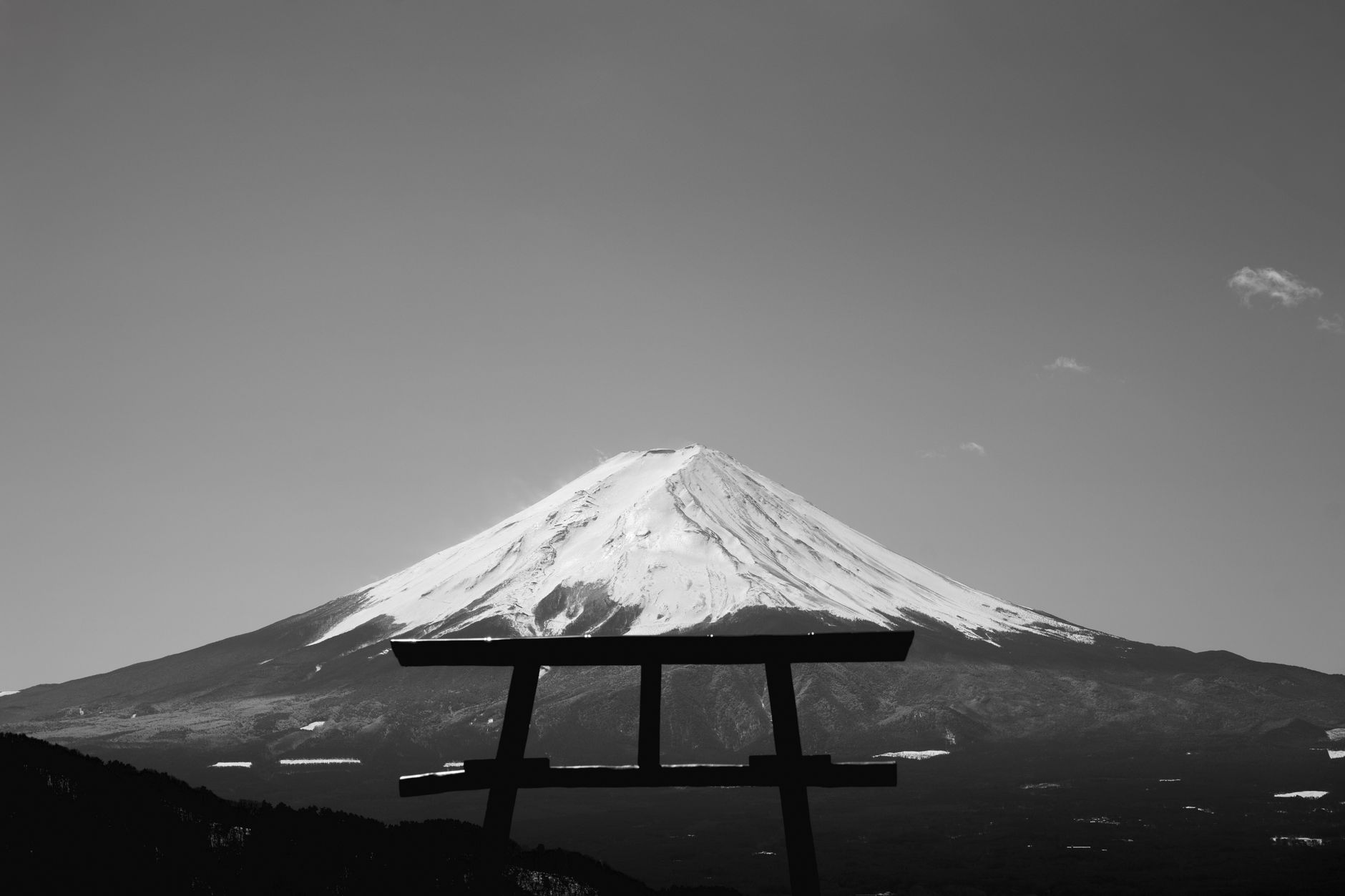 A torii gate silhouetted against Mount Fuji in black and white