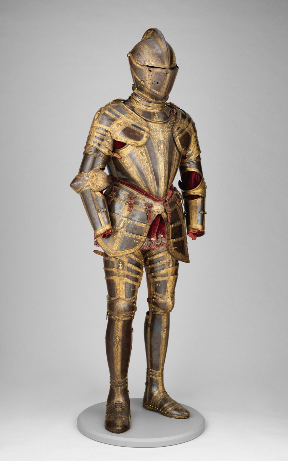 A steel armour etched and gilded with gold bands, on a stand