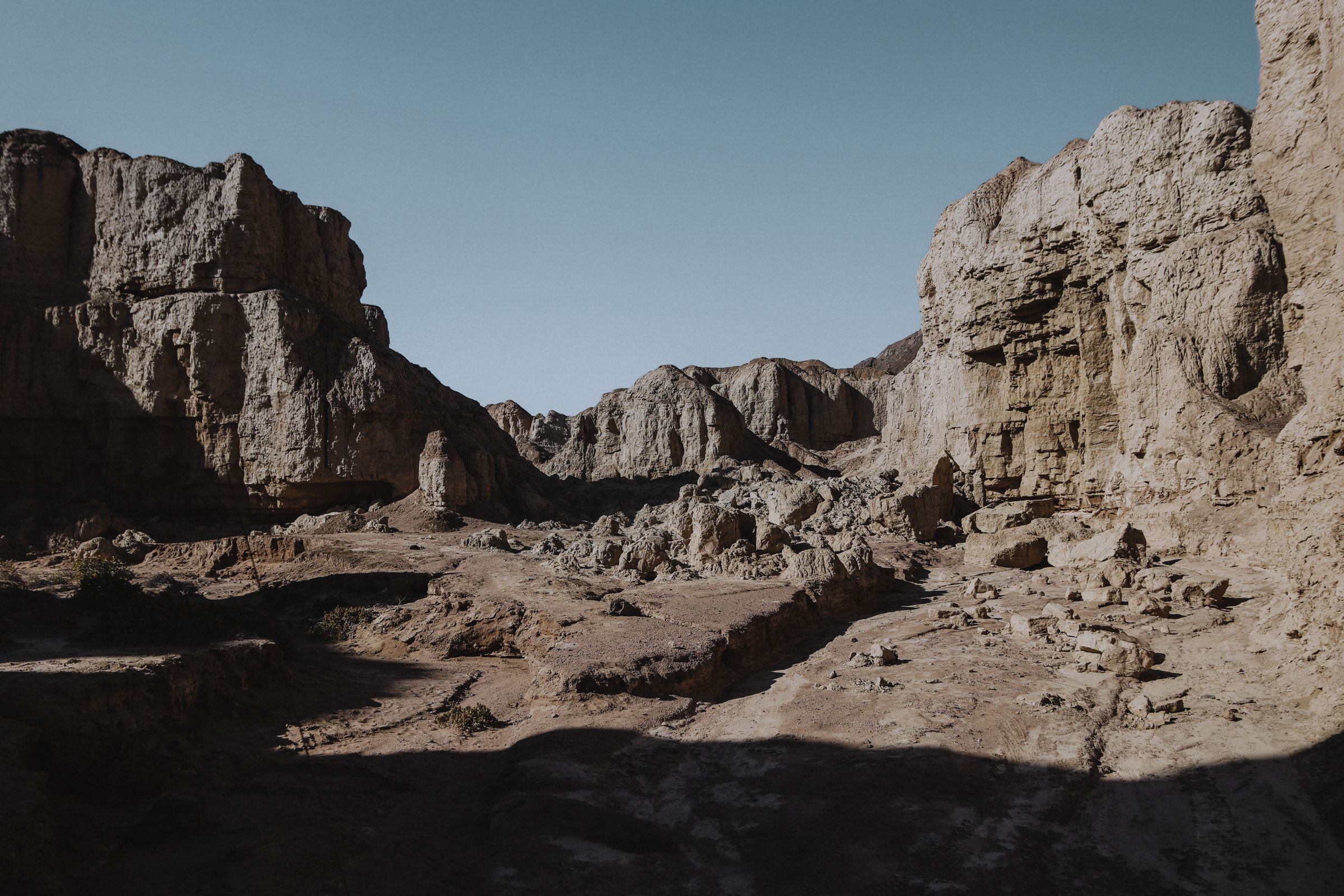 Eroded pale rock walls and rubble in a dry canyon in the Kunene region under a clear sky