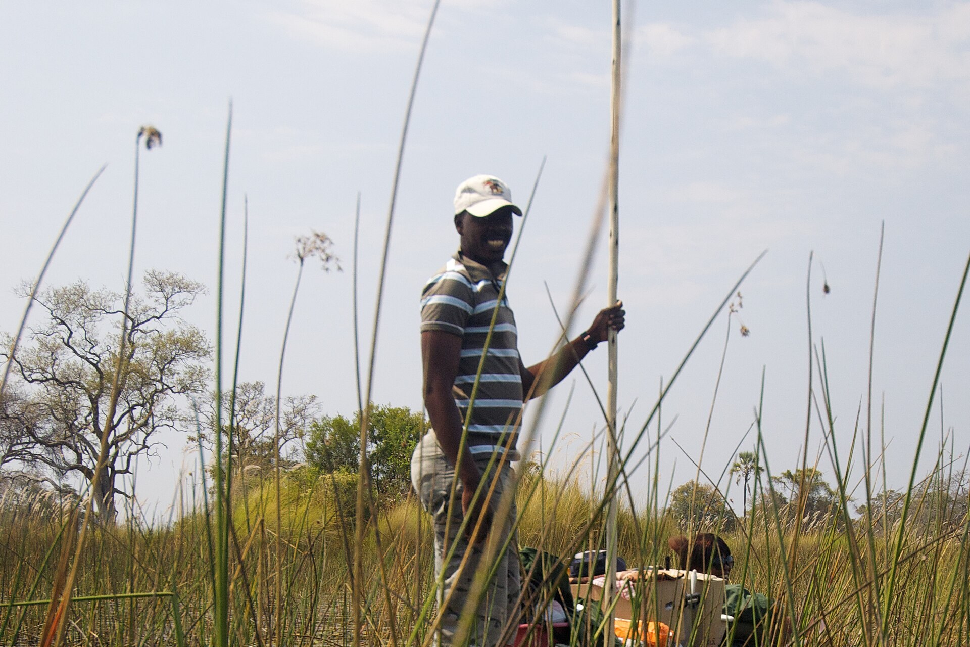 A poler standing at the stern of a mokoro dugout canoe in the Okavango
