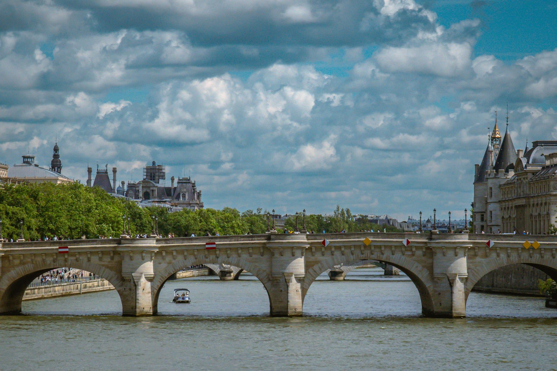 The Pont Neuf crossing the Seine at the tip of the Île de la Cité under a clouded sky