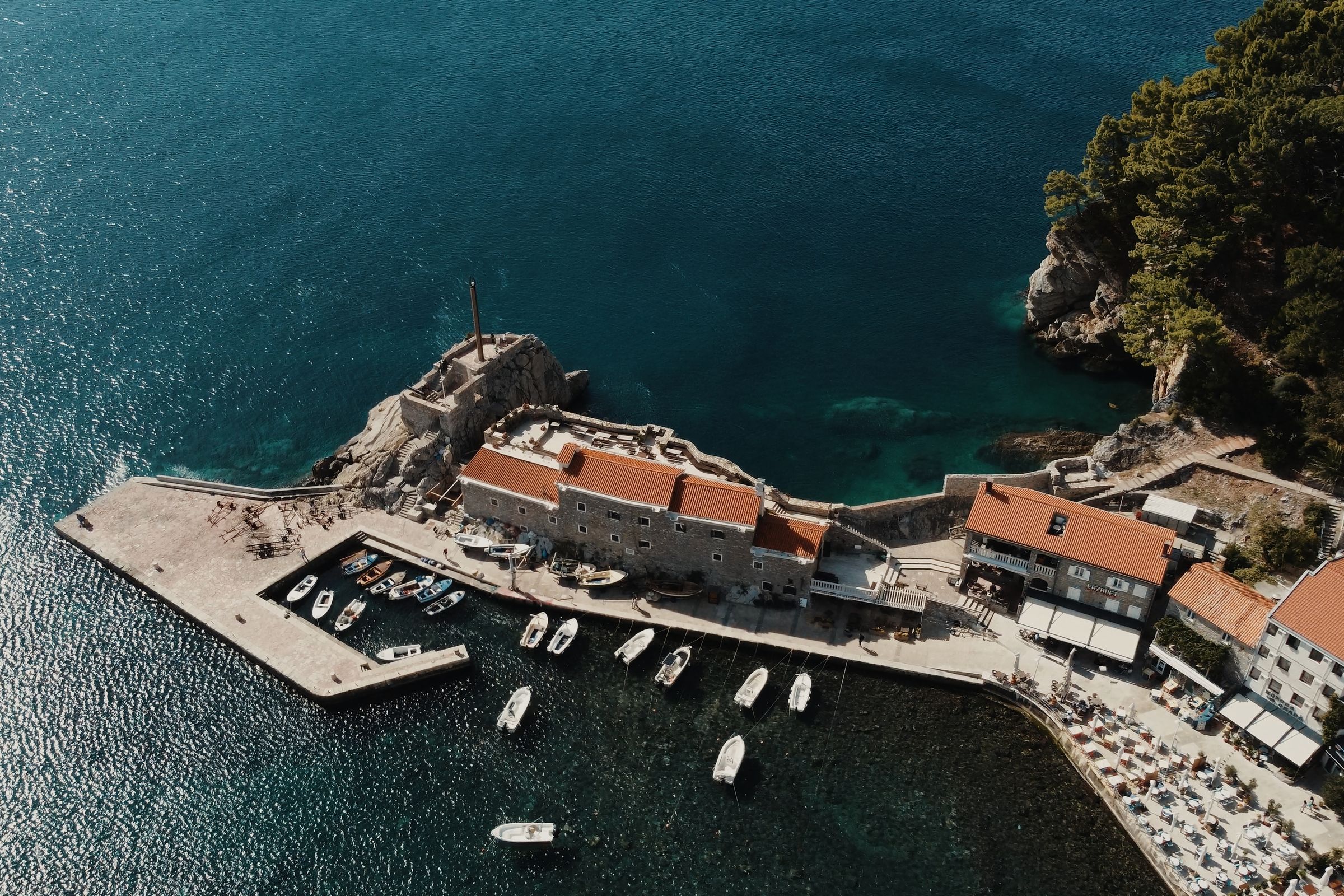 Petrovac from above: the Venetian fort on its rock, small boats in the harbour beside it and red-roofed buildings along the shore