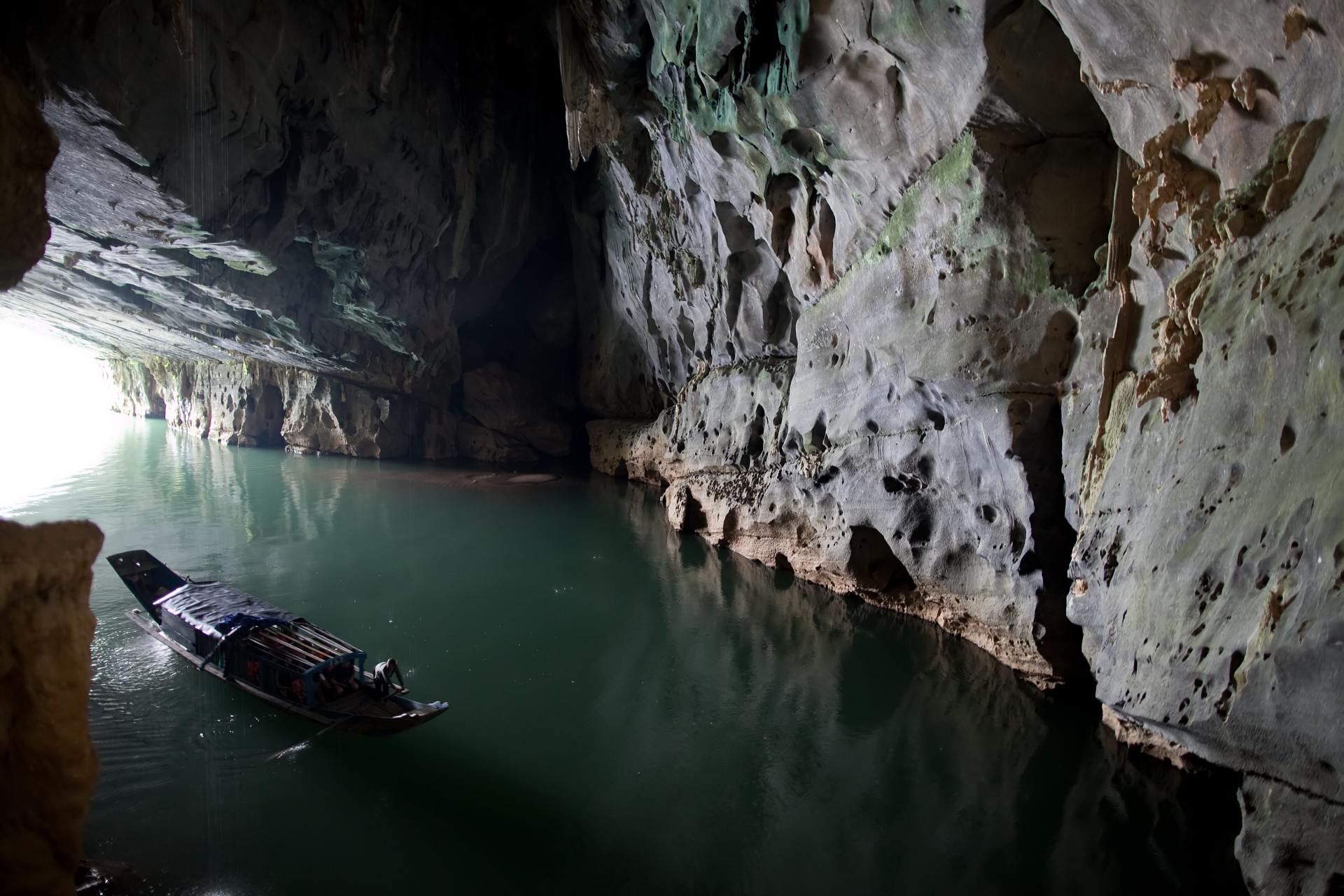 A wooden boat entering the mouth of Phong Nha Cave on the Son river