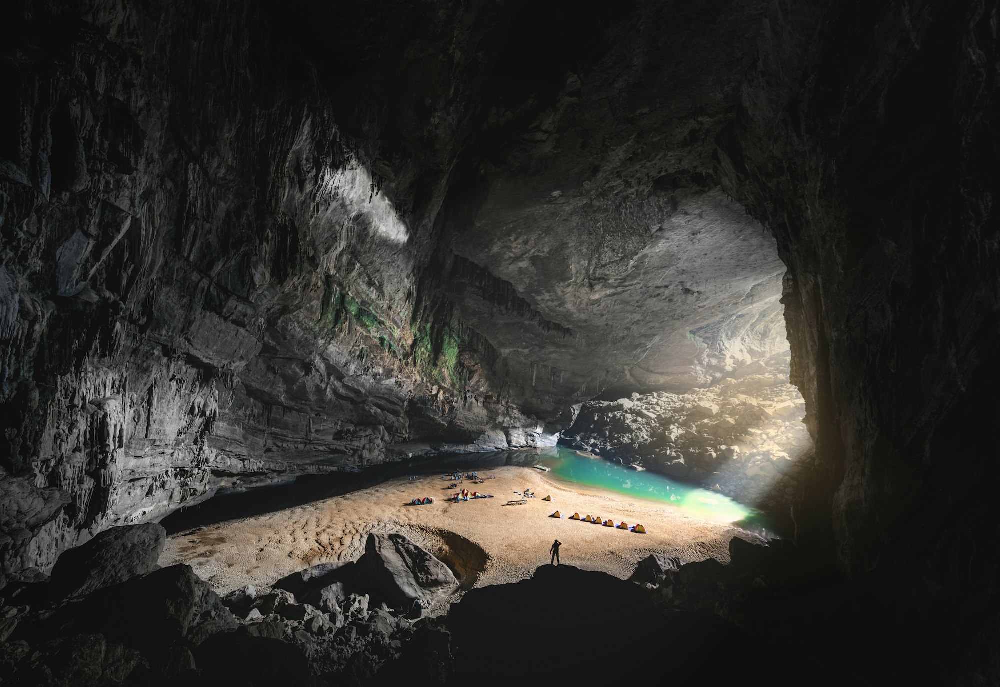 Tents on a sand beach inside the vast chamber of Hang En cave