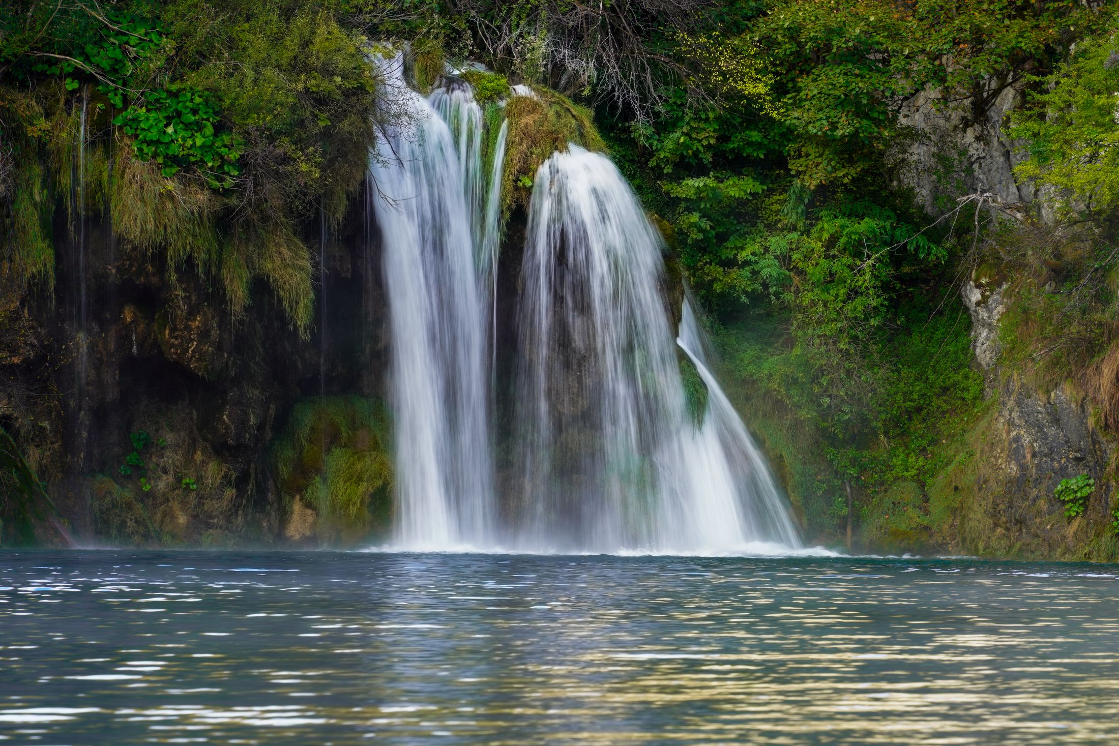 A big multi-stream waterfall dropping into a clear pool at the lower lakes of Plitvice