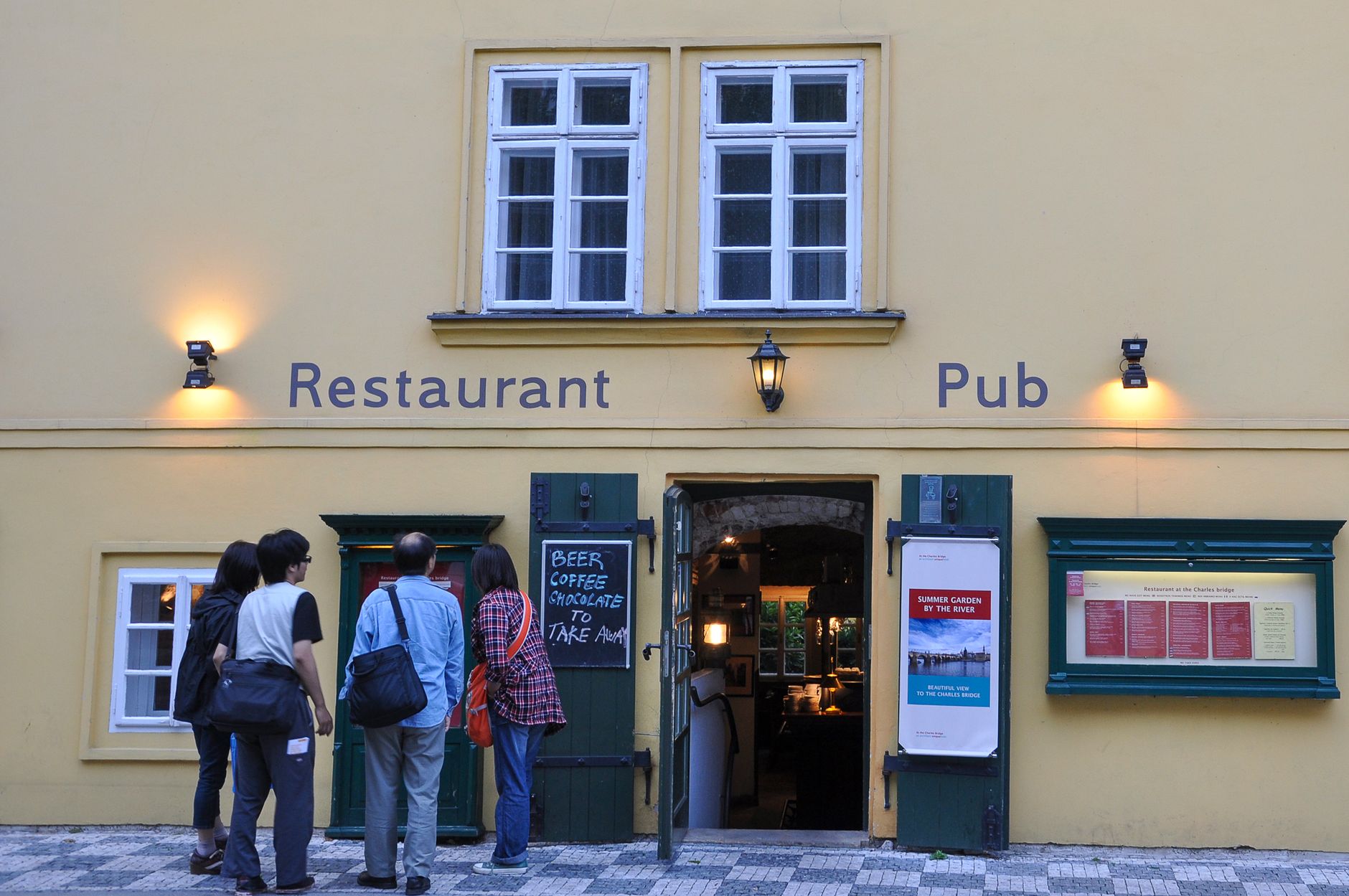 A Prague pub frontage with posted menus in a display case beside the door