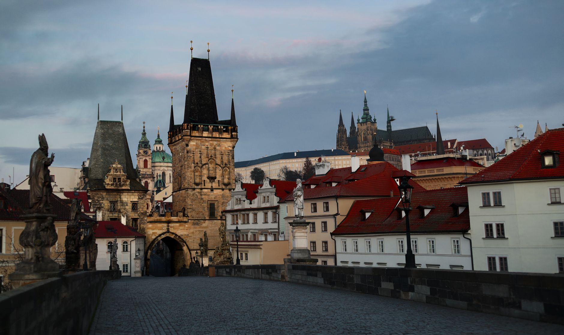 The empty deck of Charles Bridge at dawn looking towards the Lesser Town tower