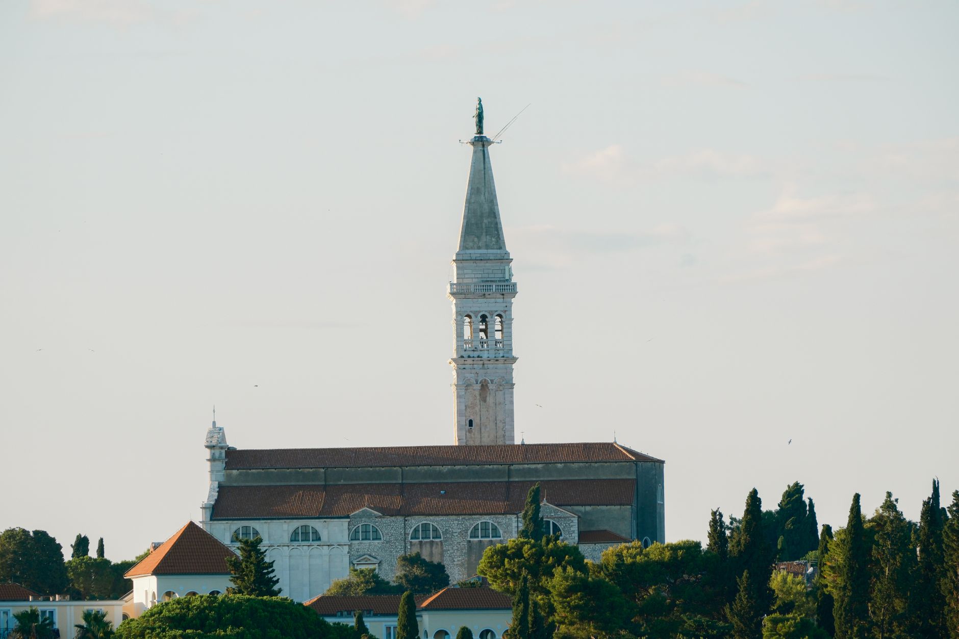 The church of Saint Euphemia and its tall stone campanile above the roofs and cypresses
