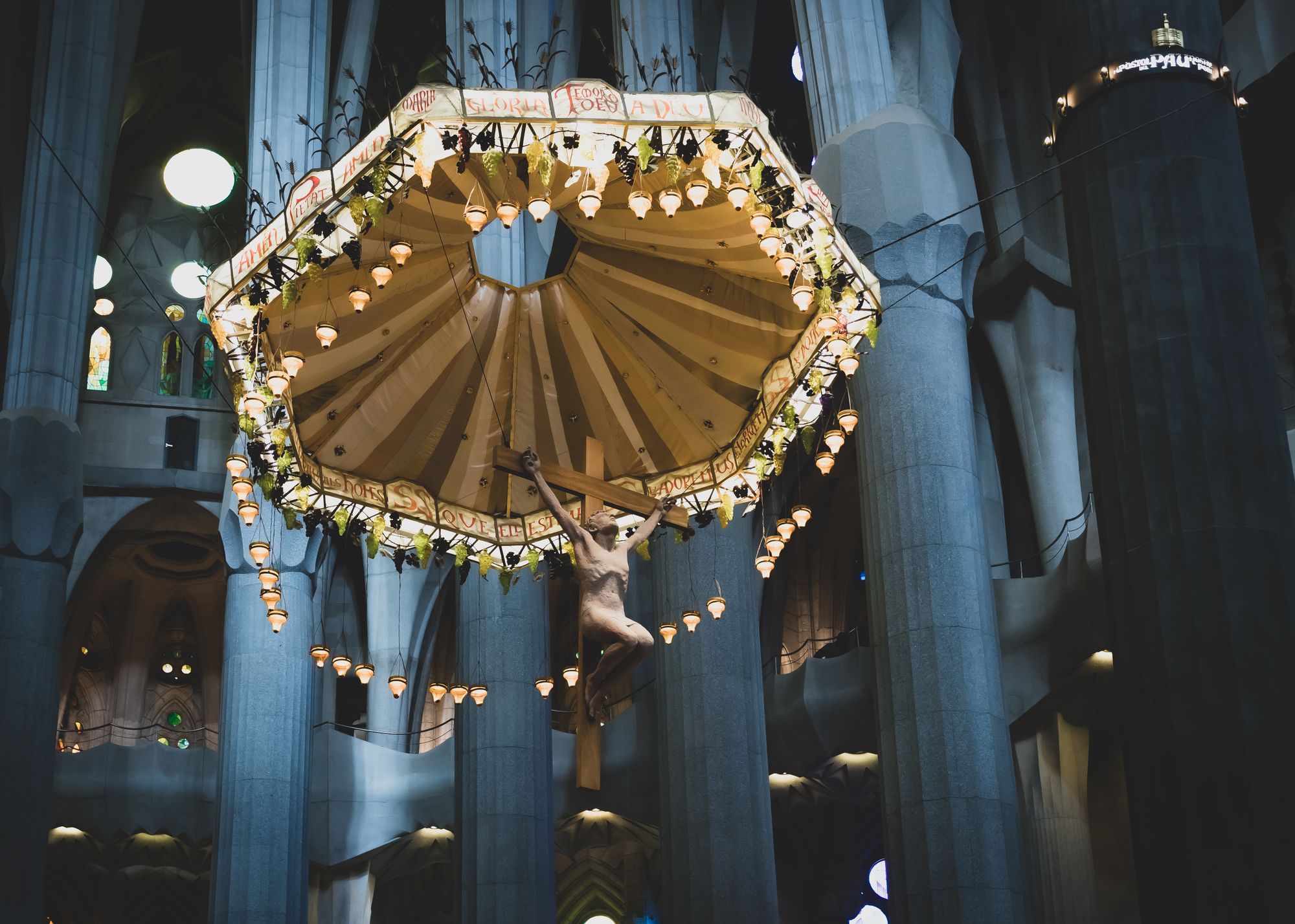The apse of the Sagrada Família with the suspended golden baldachin and crucifix above the altar, columns soaring around it