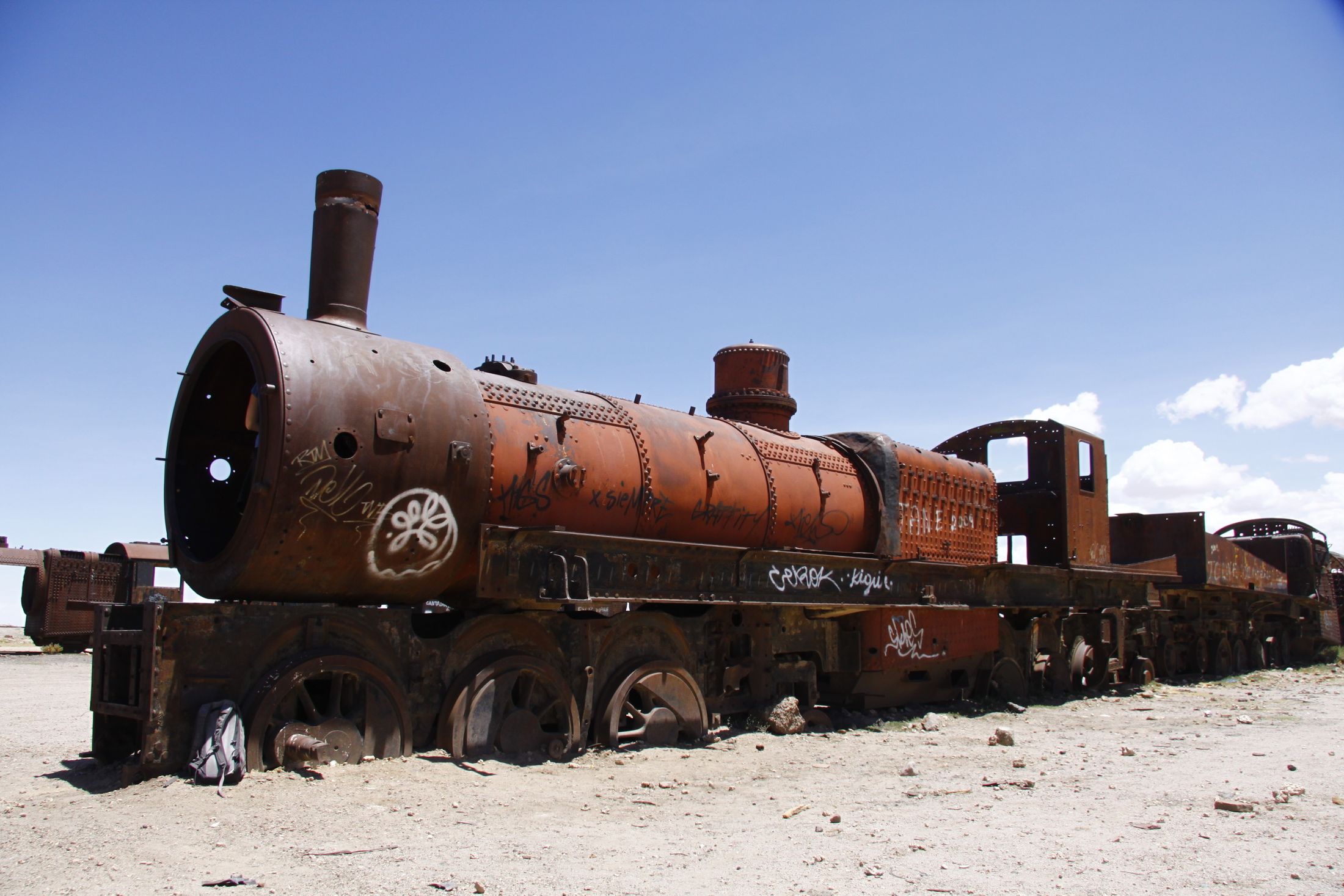 A rusted steam locomotive in the train cemetery outside Uyuni under a bright Bolivian sky