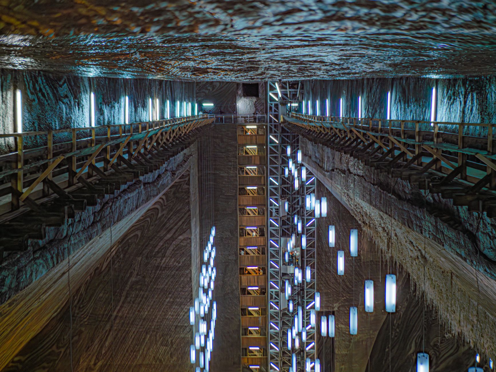 A deep lit salt chamber with timber walkways down both walls and hanging light tubes