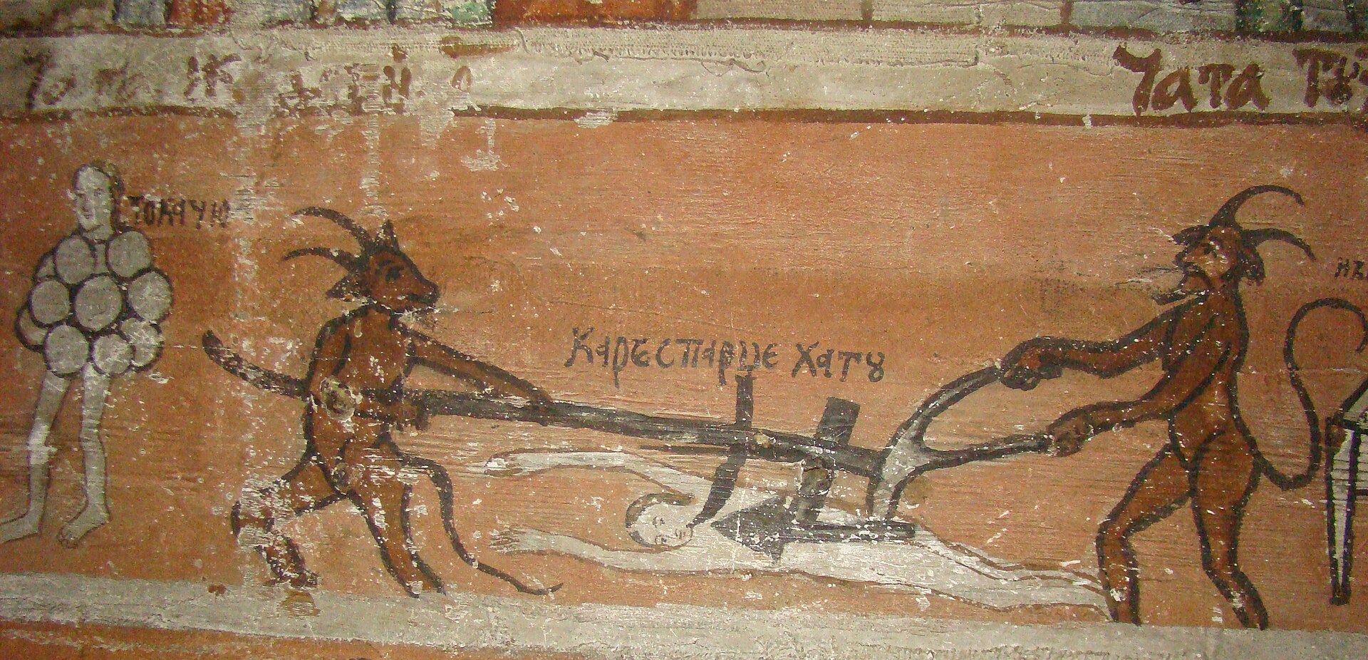 A painted church wall showing two horned devils driving a plough over a prone figure