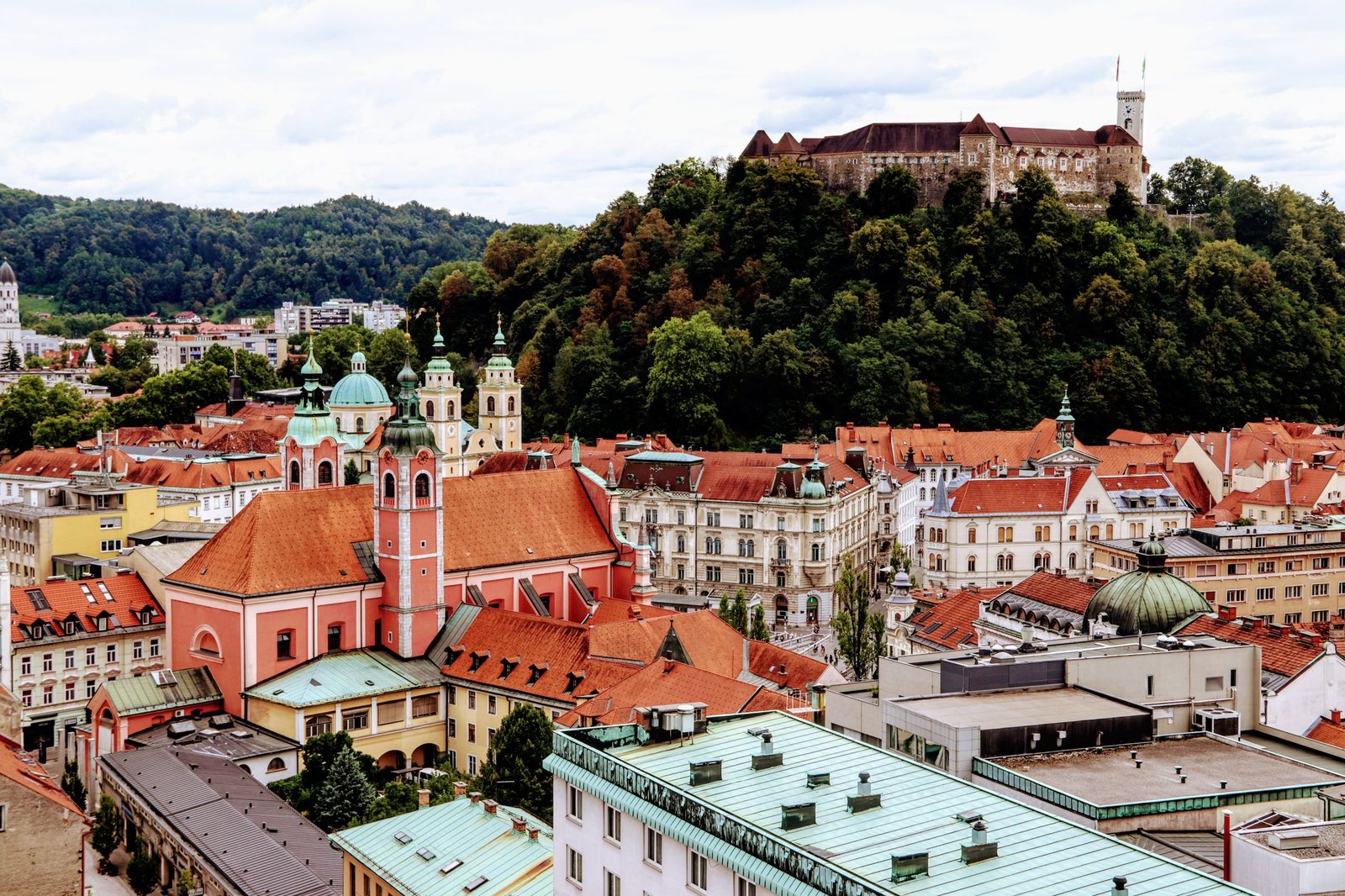 Ljubljana old town from above, red roofs and church towers below the castle on its wooded hill
