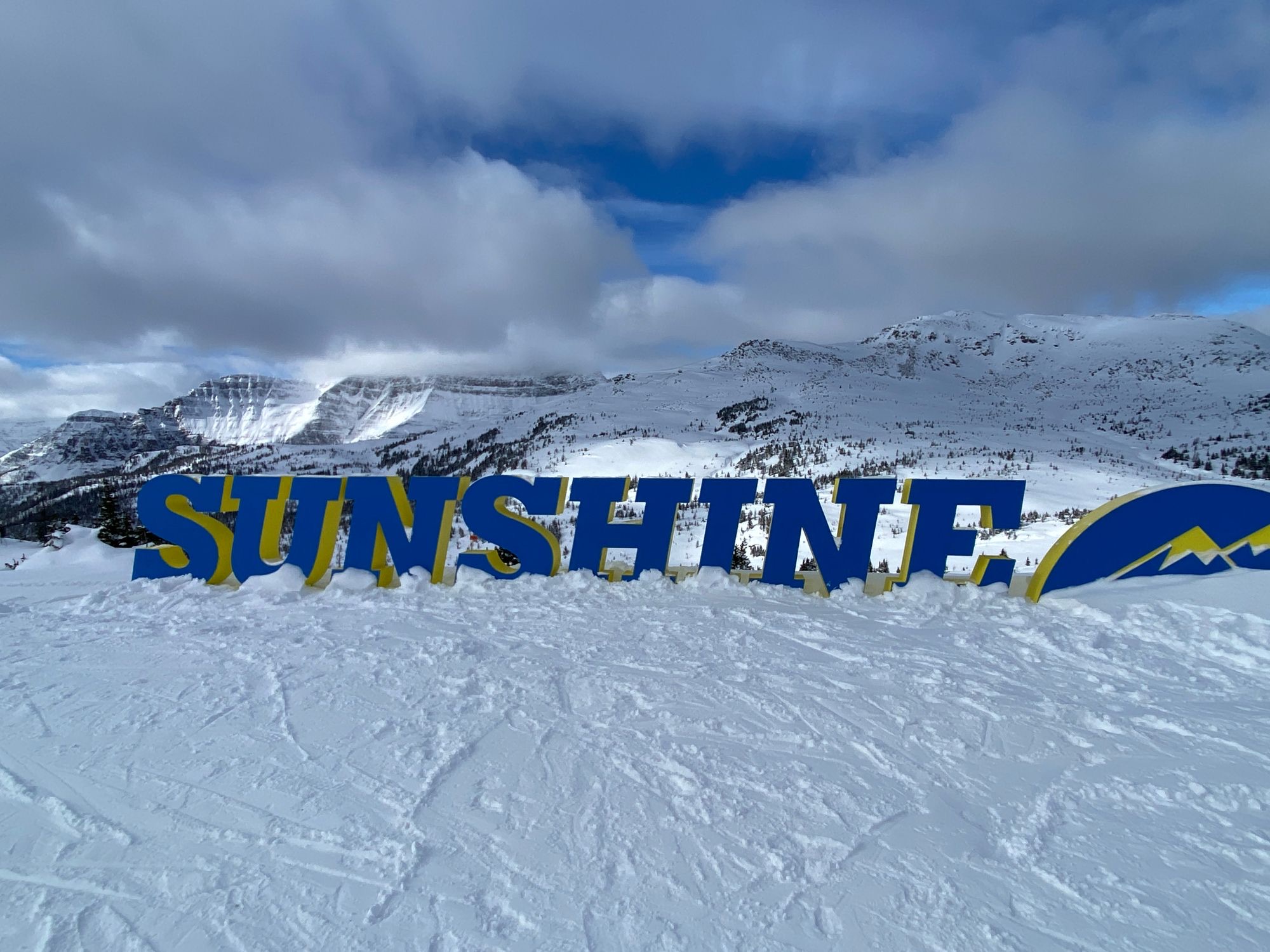Large blue SUNSHINE letters in the snow above the Village, with Lookout Mountain behind