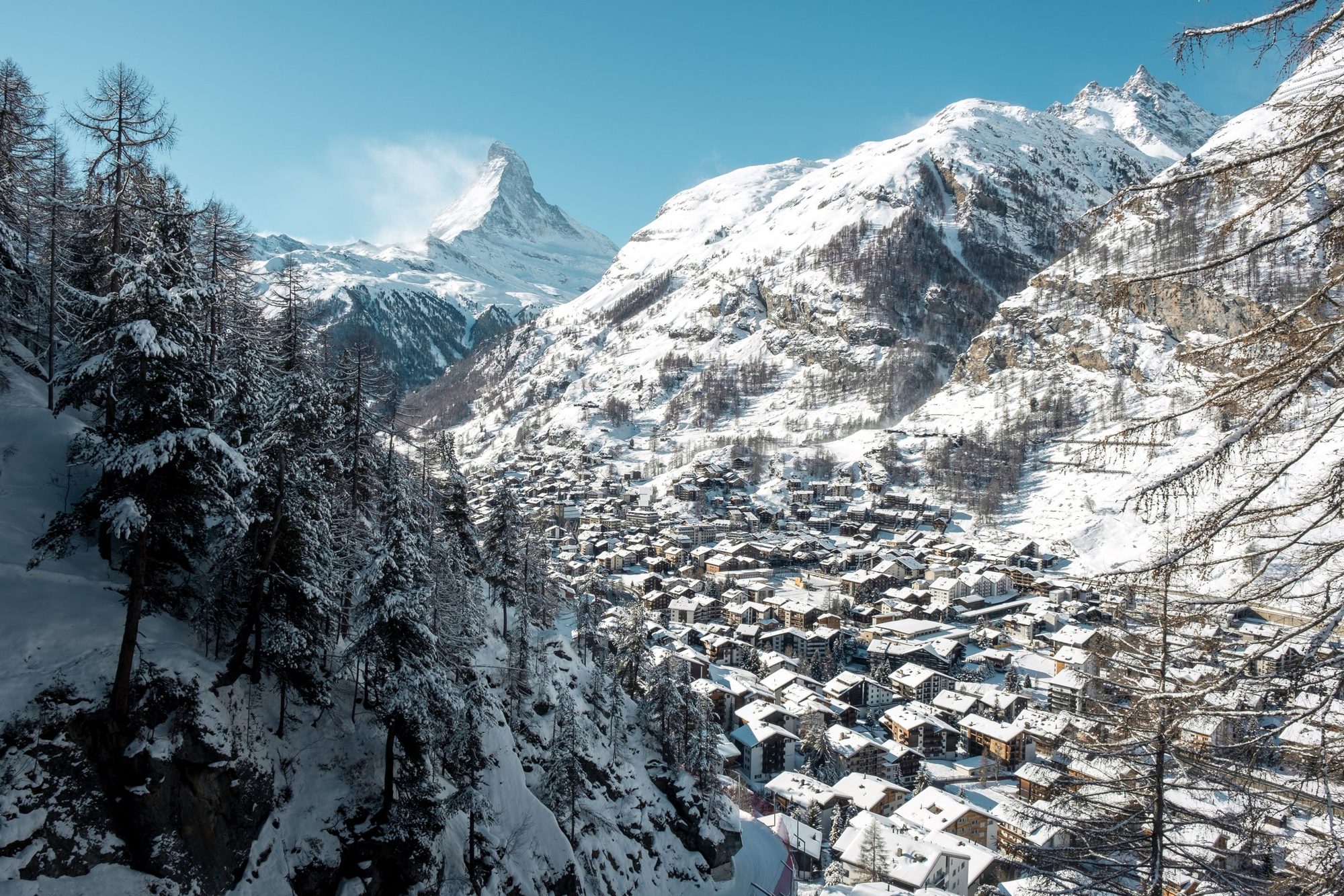 Zermatt under deep snow seen from the forest above, with the Matterhorn at the head of the valley