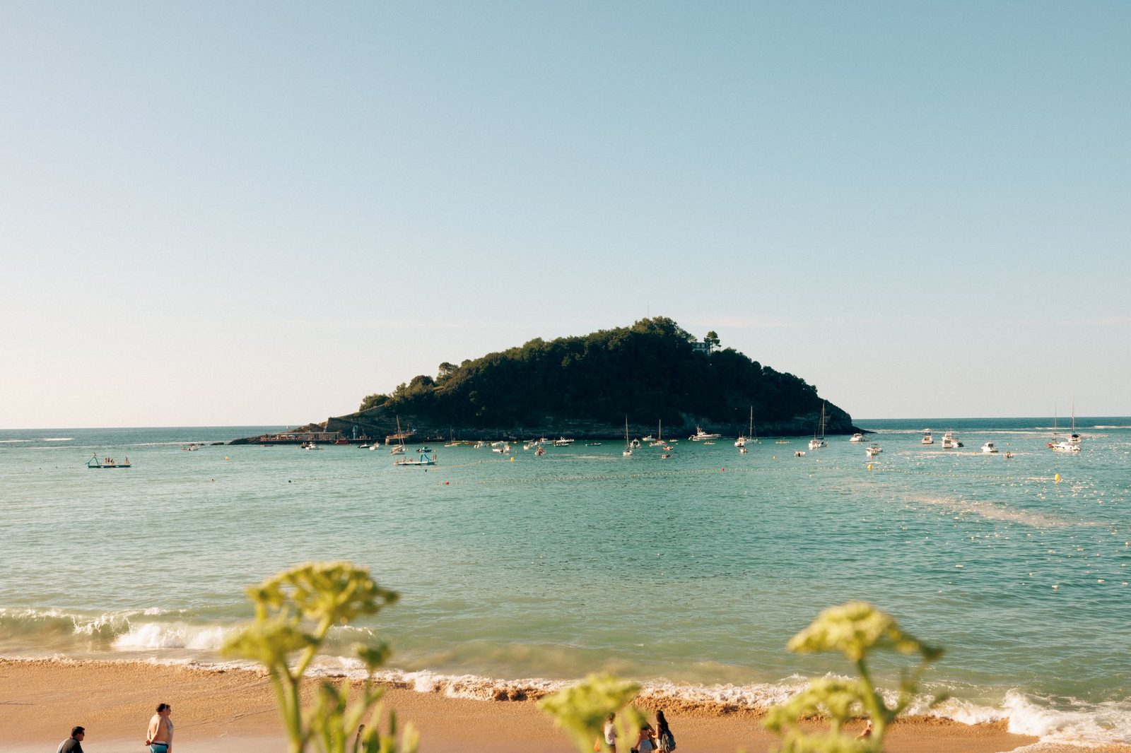 La Concha bay in San Sebastián on a summer day, small boats at anchor and the green island of Santa Clara in the middle of the bay