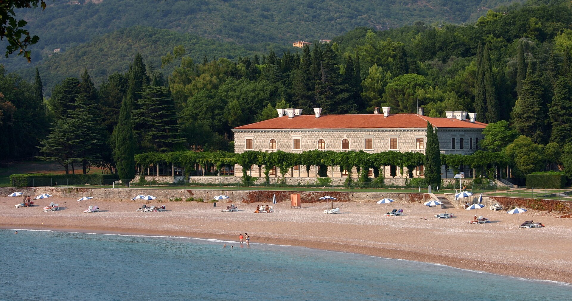 Villa Miločer, a low stone building with an arcaded terrace, standing among pines above the sea