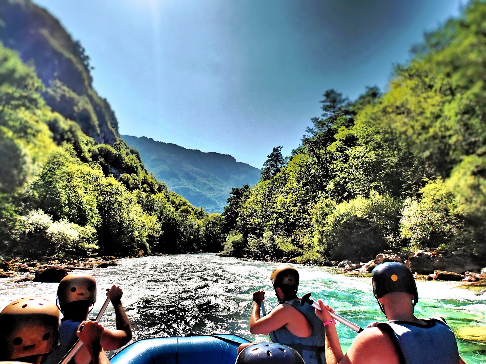 A raft of paddlers in helmets and lifejackets running clear water in the Tara canyon