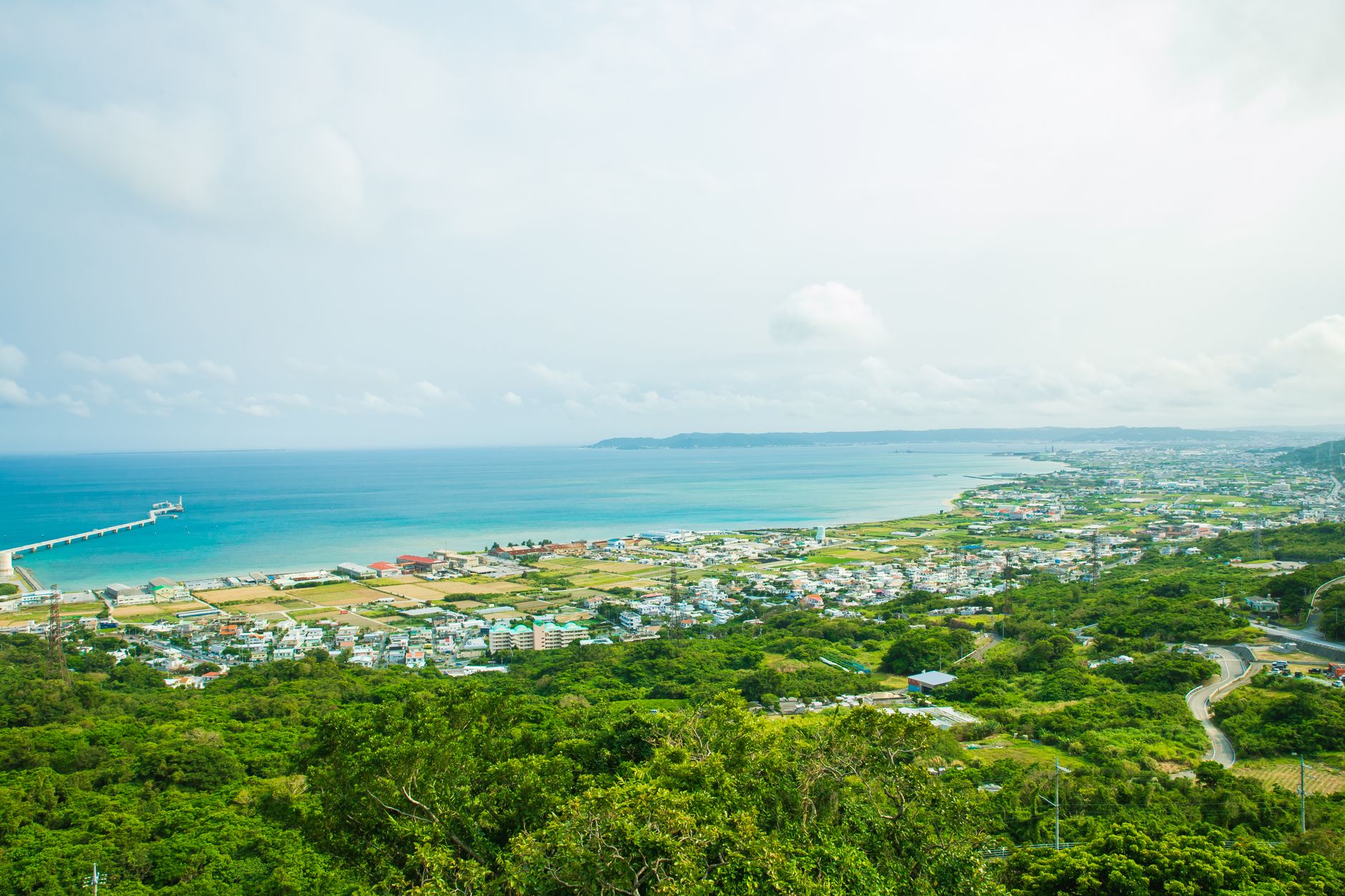 The turquoise coast of Okinawa with green hills above the sea