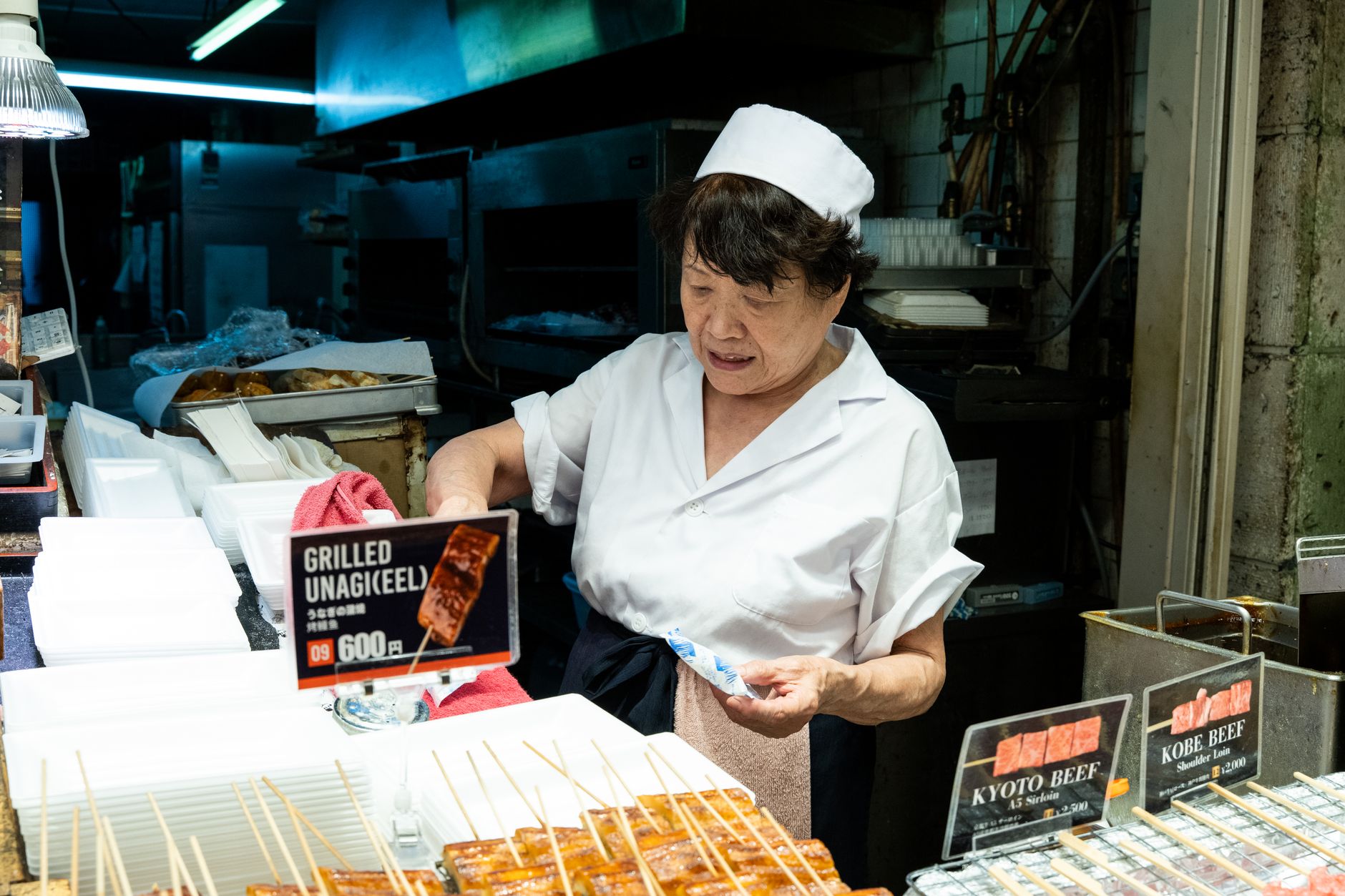 A Japanese cook grilling unagi eel over charcoal at a market
