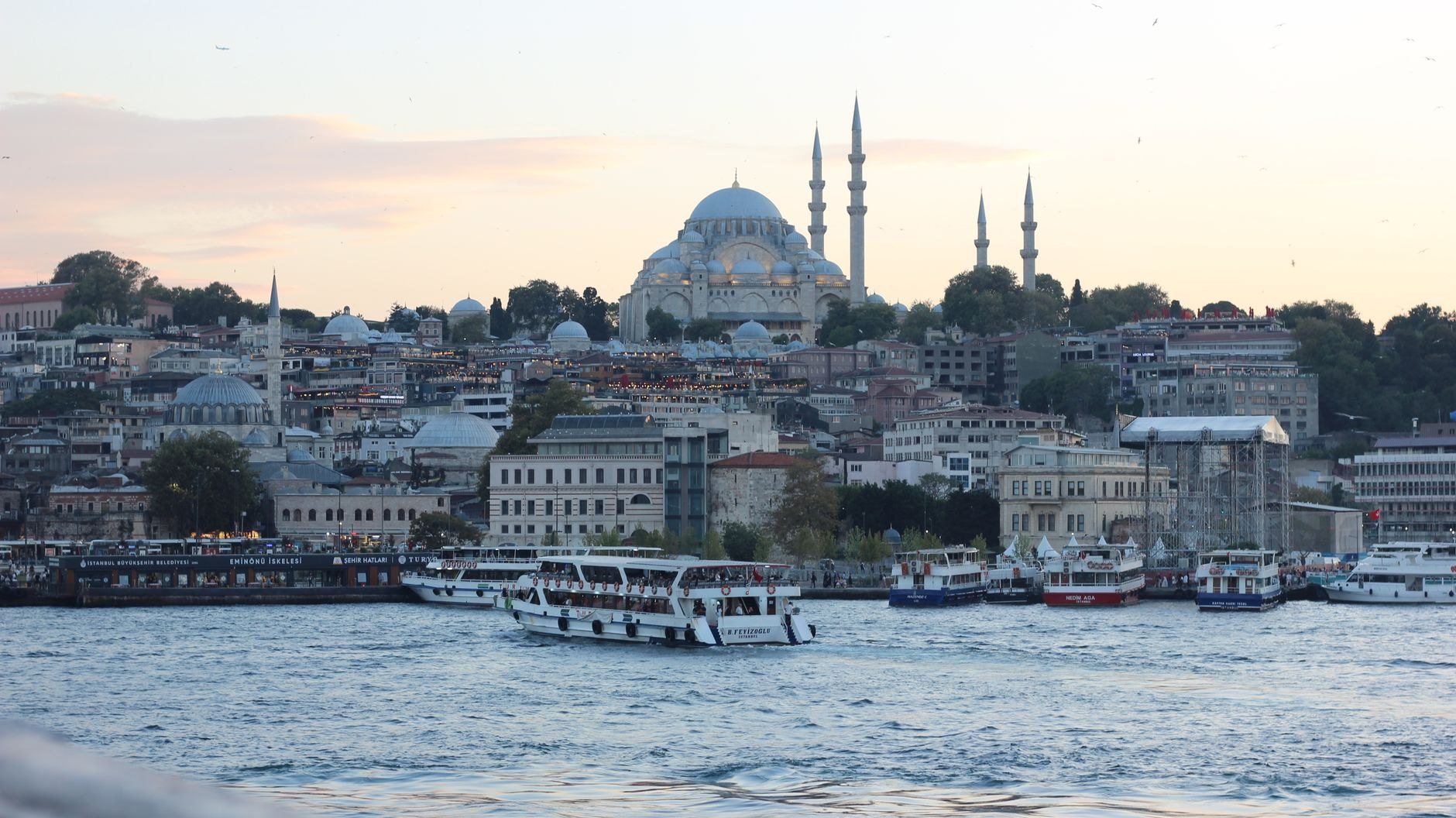 The domes and four minarets of the Suleymaniye Mosque on the ridge above the Golden Horn, with commuter ferries crossing the water below