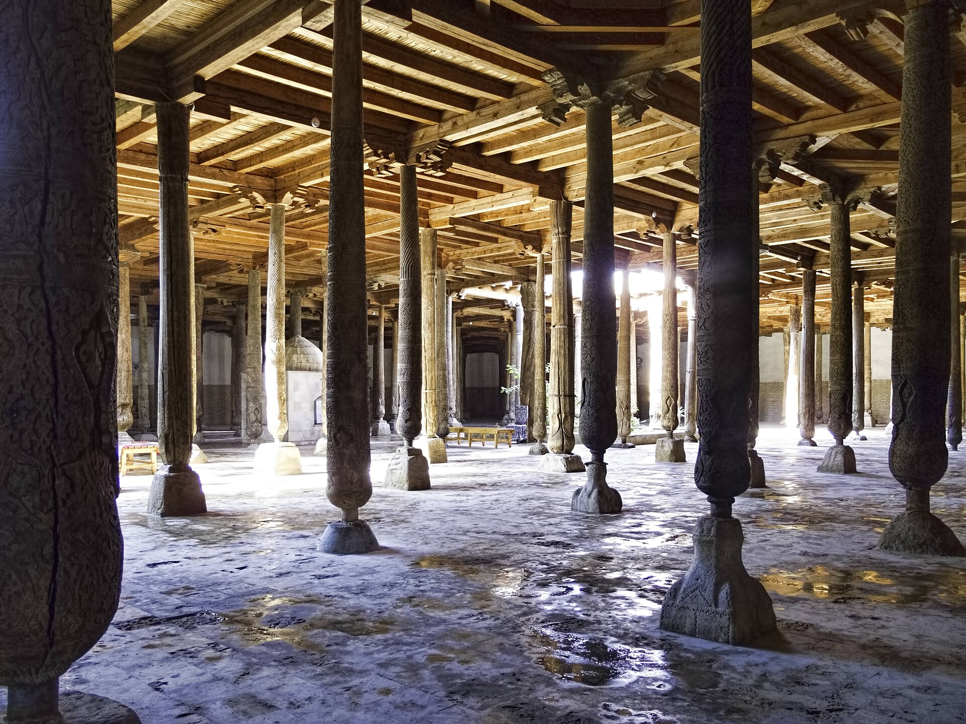 The forest of carved wooden columns inside the Juma Mosque in Khiva, lit by shafts of daylight