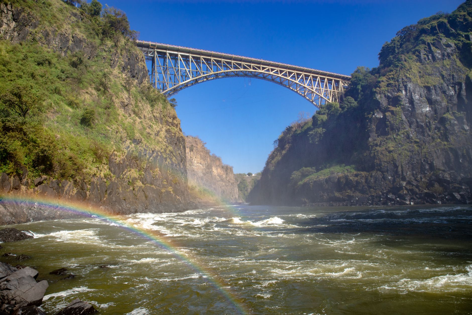 Rainbow arcing across the Zambezi gorge beneath the Victoria Falls Bridge