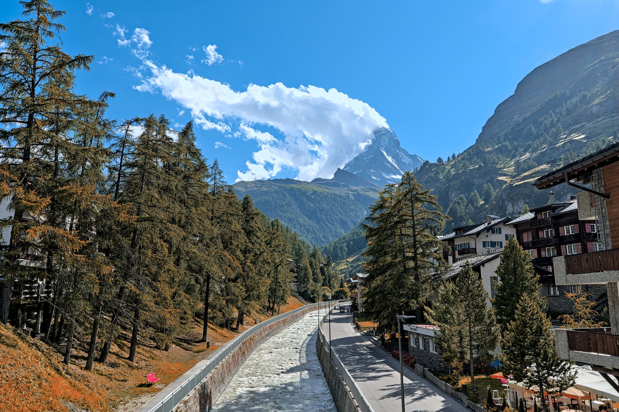 The Matterhorn at the head of the valley above Zermatt, with larches in autumn colour and chalets beside the Vispa river
